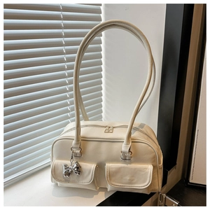 Detail der cremeweißen Schultertasche aus Kunstleder mit Taschen und Schleifenanhänger