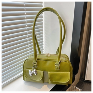 Detail der grünen Schultertasche aus Kunstleder mit Doppeltaschen und Schleifenanhänger