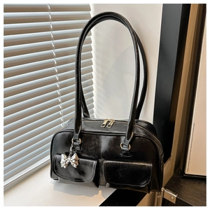 Detailansicht der schwarzen Retro-Handtasche mit Vordertaschen und Silberbogen-Charm