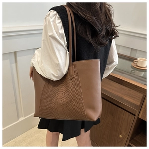 Detailed view of brown tote bag with snake pattern texture on a model's shoulder