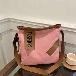 Sac cabas en toile rose avec lanières brunes et patch mode dans un café chic