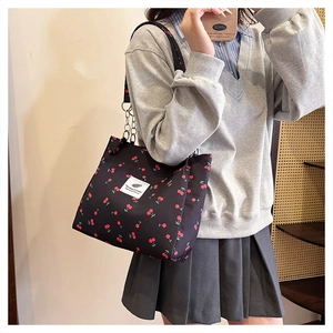 Close-up of black canvas tote bag with cherry print and metal chain strap details
