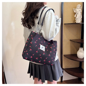 Detail of cherry print tote bag with metal chain strap worn over the shoulder
