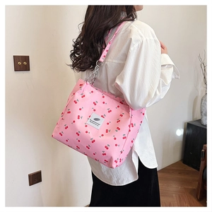 Side view of pink cherry print tote bag with woven label shown on female model