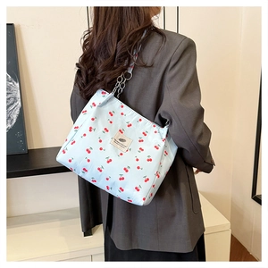 Close-up of light blue underarm bag with cherry print and metallic chain strap detail