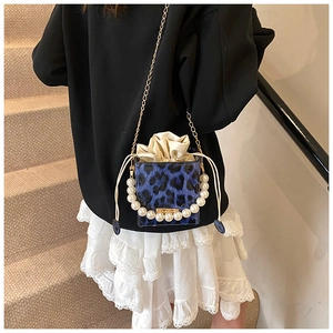 Detalle del mini bolso de leopardo azul con asa de perlas y correa de cadena dorada