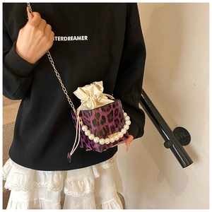 Detalle de mini bolso de leopardo púrpura con asa de perlas y cadena dorada