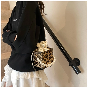 Detalle de bolso saco de leopardo con asa de perlas y correa de cadena dorada