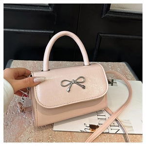 Detail shot of pink bow knot metal buckle and glossy cracked texture PU leather bag