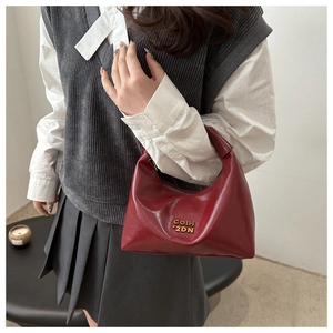 Detailed close-up of a burgundy crescent moon bag with a metallic gold logo and zipper