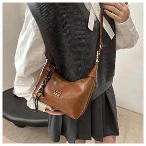 Macro view of vintage brown oil leather handbag with braided fringe and metal bell charm