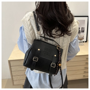 Macro shot of black vintage PU leather crossbody bag featuring gold hardware and bell charm