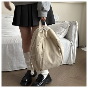 Dettaglio zaino in nylon beige con tasche verticali con zip e maniglia superiore