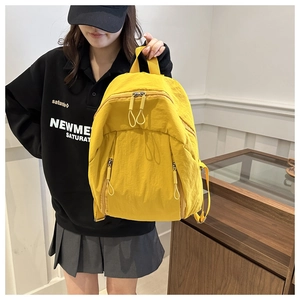 Dettaglio dello zaino in nylon giallo con tasche multiple e tiretti lunghi in corda