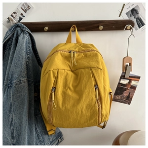 Dettaglio dello zaino in nylon giallo con doppie cerniere su gancio in legno scuro