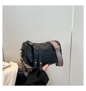 Detail of black cylindrical pillow bag with wide red wave strap and gold hardware