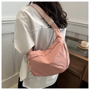 Pink nylon crescent crossbody bag featuring adjustable drawstring detail and silver zipper