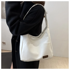 Dettaglio della borsa hobo in pelle opaca bianca con etichetta marrone su cappotto nero