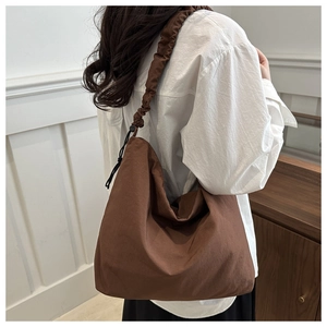 Detail of a dark brown nylon hobo bag featuring a scrunchie shoulder strap and retro style