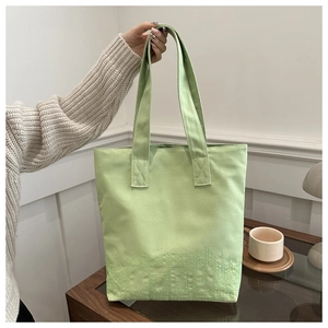 Détail du sac cabas en toile vert clair avec broderie de lettres texturées élégantes