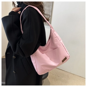 Dettaglio di una borsa tote in nylon rosa con una piccola toppa logo in pelle marrone