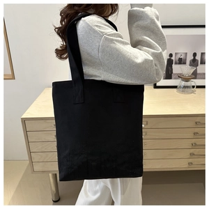 Detail shot of large black canvas tote bag showing thick durable fabric and wide straps