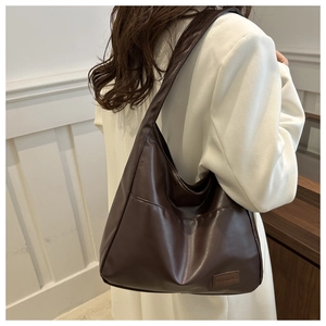 Dettaglio della borsa tote in pelle PU marrone scuro con logo e ampia tracolla