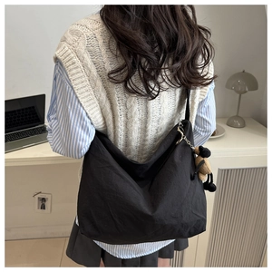 Detailed view of black nylon dumpling bag with cute brown bear charm for daily use