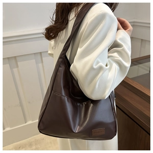 Dettaglio della borsa tote vintage marrone scuro con logo e tasca frontale per il lavoro