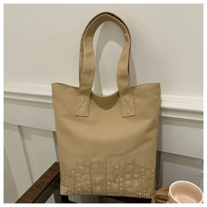 Detailed close-up of khaki canvas tote bag featuring embroidered KTMU text and fabric texture