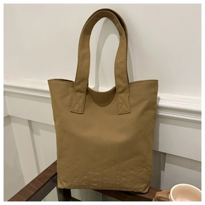 Close-up of khaki canvas tote bag featuring decorative skyline stitching and wide handles