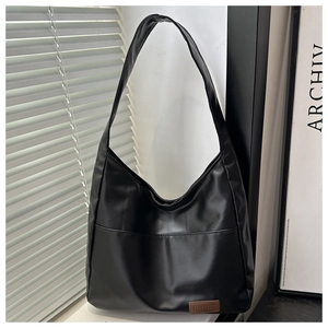Dettaglio di una borsa hobo nera minimalista con etichetta in pelle marrone sopra