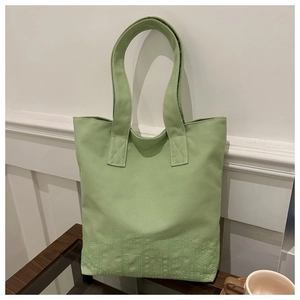 Detail of light green canvas tote bag showing reinforced stitching and subtle embroidery