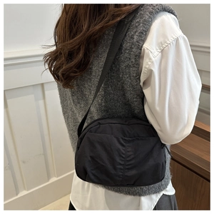Rear view of model wearing a black pleated nylon crossbody bag with adjustable strap