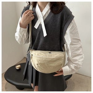 Lifestyle shot of an off-white crescent crossbody bag with adjustable strap and zip closure