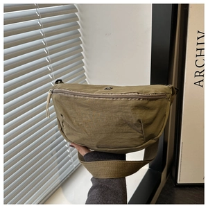 Detail view of khaki nylon saddle bag showing smooth zipper and durable shoulder strap texture