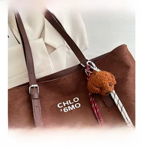 Detail of matte brown tote bag with white lettering and cute puppy plush pendant