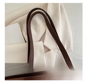 Detail of dark brown suede tote bag featuring smooth leather handles and silver hardware