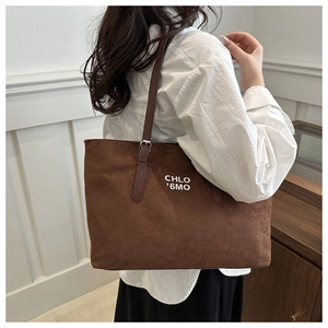 Detail of a large brown suede tote bag with white lettering for stylish daily commuting