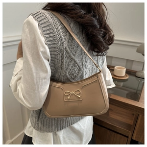 Detail of elegant beige crescent shoulder bag with golden metallic bow buckle
