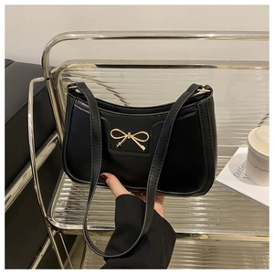 Close-up of black PU leather crescent bag featuring a golden bow metal buckle detail