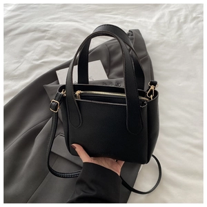 Detail of black lychee grain leather bucket bag with gold hardware and dual handles
