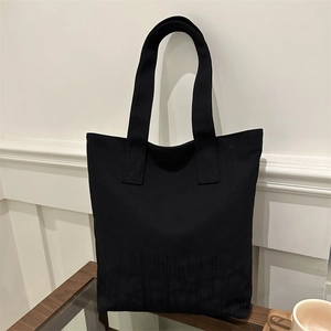 Sac fourre-tout noir minimaliste avec base texturée présenté sur une table en bois chic