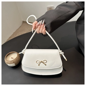 Détail du sac selle en cuir PU blanc avec boucle en nœud doré et bandoulière nouée