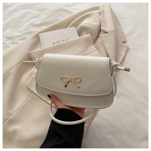 Détail de la boucle en métal doré en forme de nœud sur le sac à main en cuir blanc