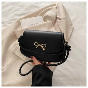 Détail d'un sac en cuir noir avec boucle nœud dorée et bandoulière en corde nouée