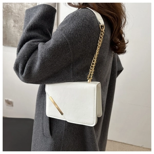 Detailed side view of white crossbody chain bag on a model wearing a grey wool coat