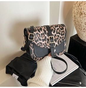 Detail of leopard print leather handbag with gold buckle closure and sleek black trim