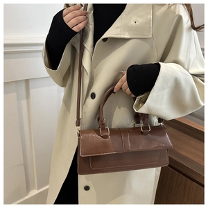 Detail of dark brown leather satchel with gold hardware and stylish long shoulder strap