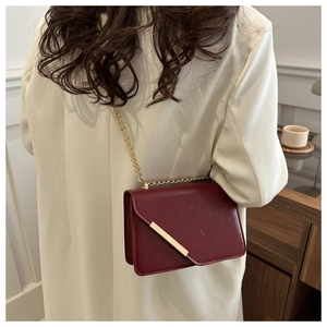 Back view of model wearing burgundy leather crossbody bag with elegant gold chain strap